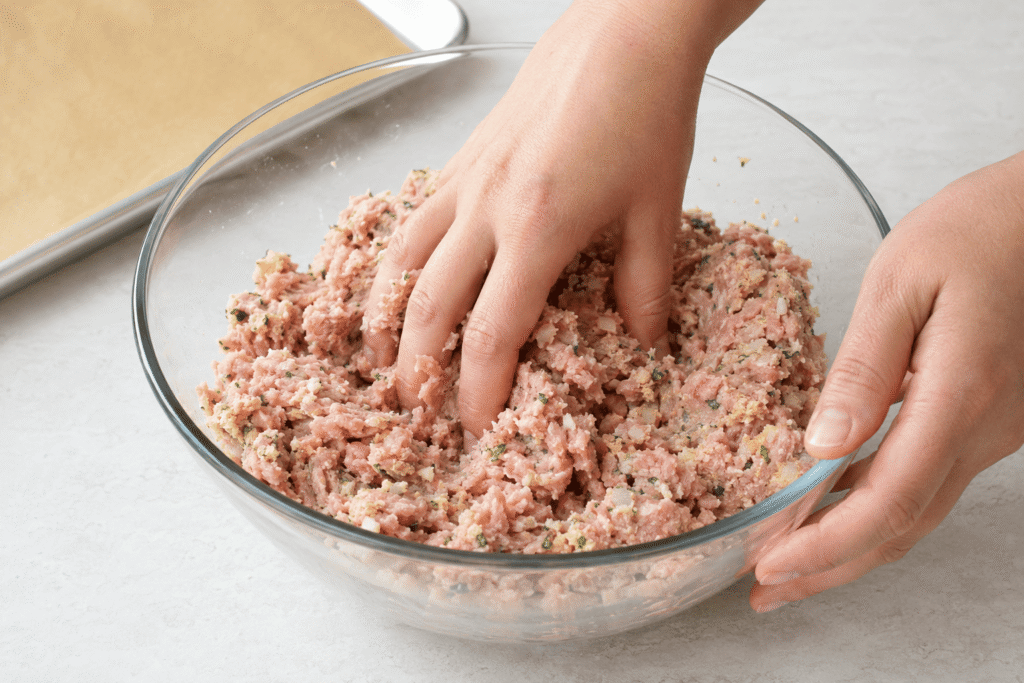 Ground turkey being gently folded into the breadcrumb and herb mixture
