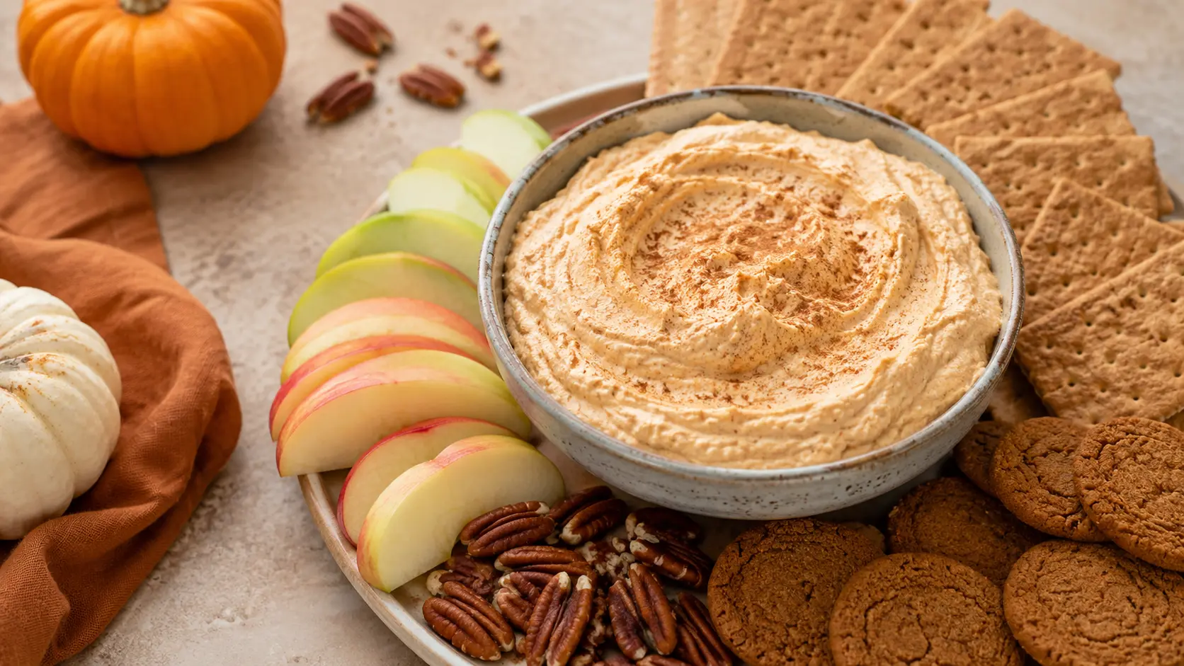 Easy no-bake pumpkin cheesecake dip served with graham crackers, cookies, apple slices, and pecans