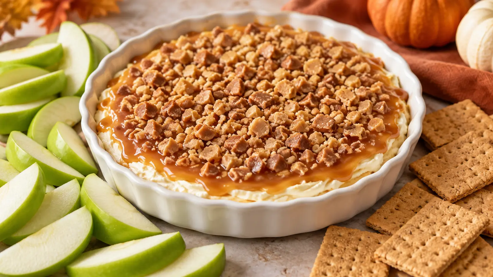 Caramel apple cheesecake dip topped with caramel and crunchy toffee, served with sliced Granny Smith apples and graham crackers